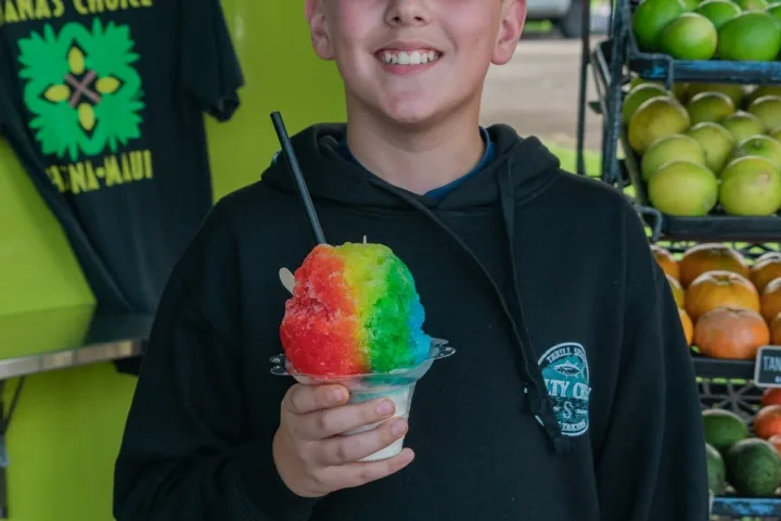 a person holding a donut in front of a store