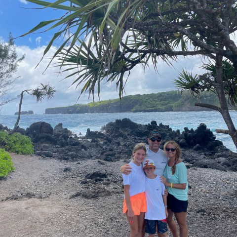 a group of people standing next to a palm tree on a beach