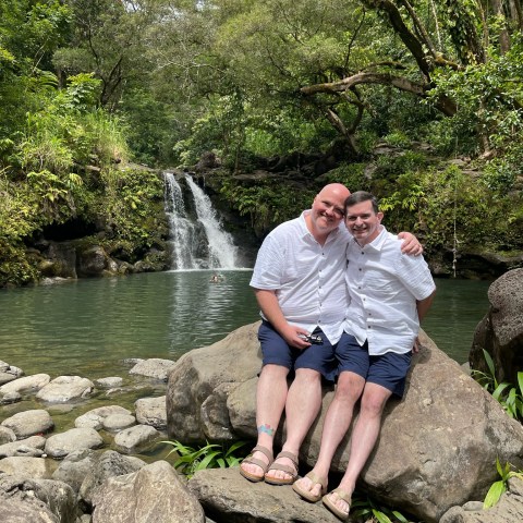 a man sitting on a rock next to water