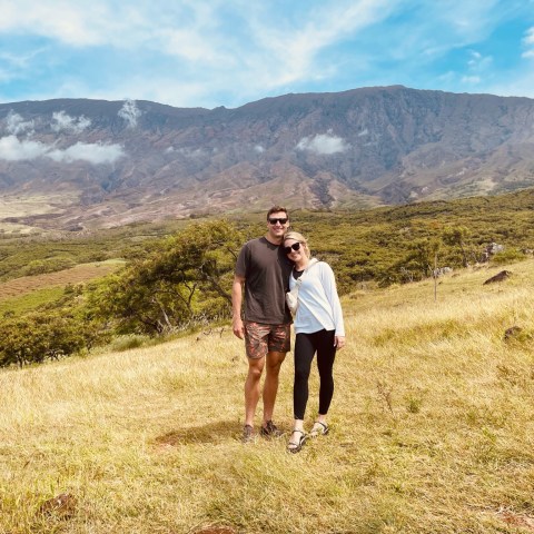 a man standing in a field with a mountain in the background