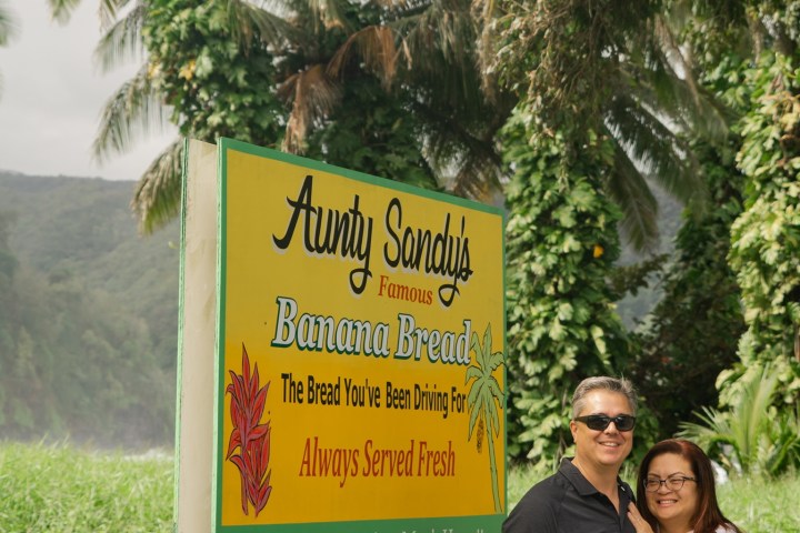 a person standing next to a palm tree in front of a sign