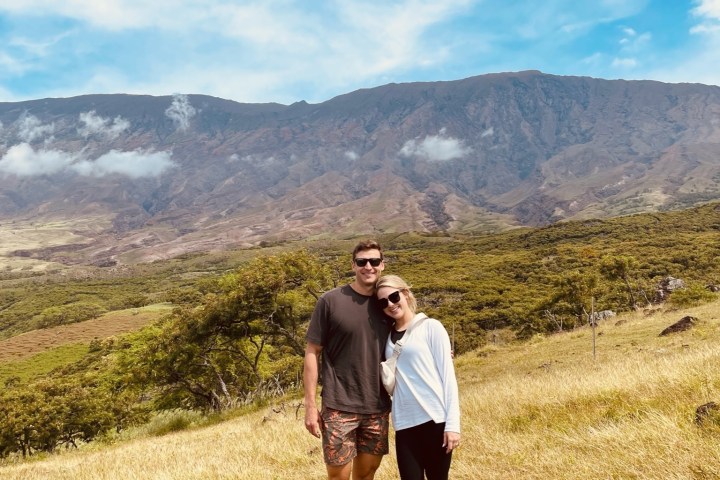 a man standing in a field with a mountain in the background