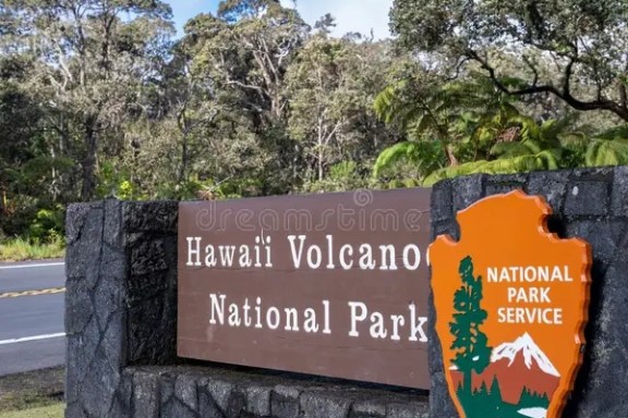 Entrance sign to Hawaii Volcanoes National Park with trees in background.